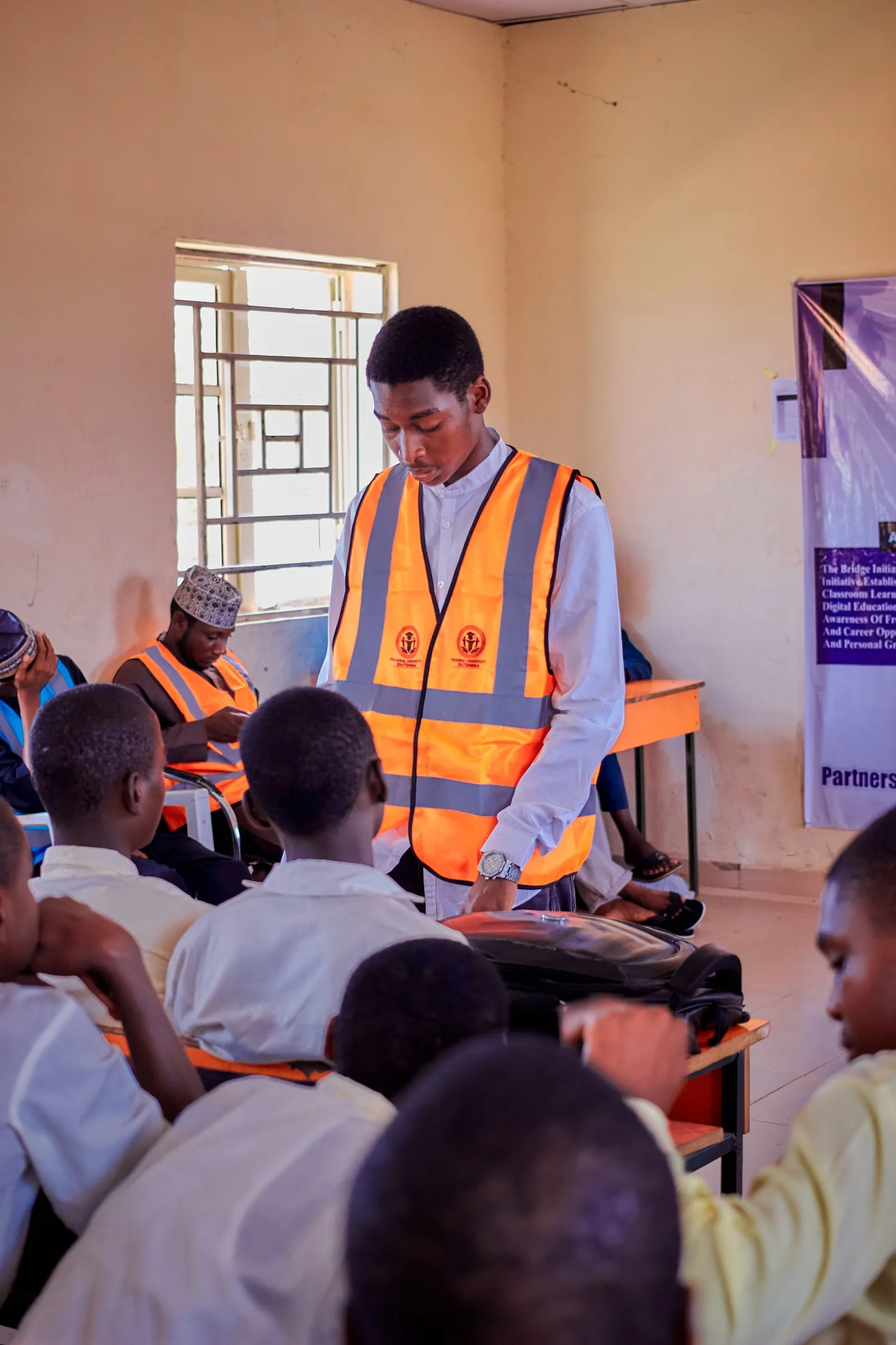 A volunteer in an orange vest guiding students during a school outreach. Photo by QS.Pexel on Pexels.